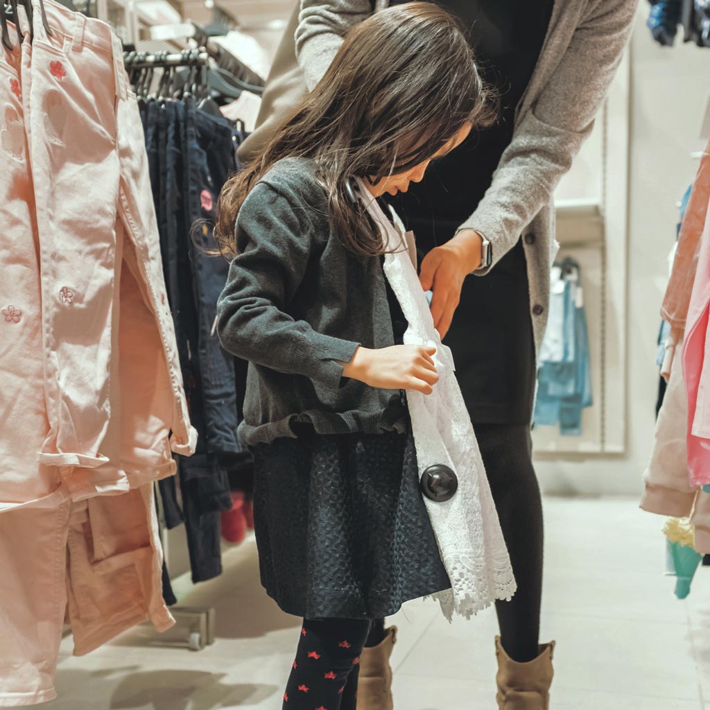 fox and aikins child trying on clothes at local retail store